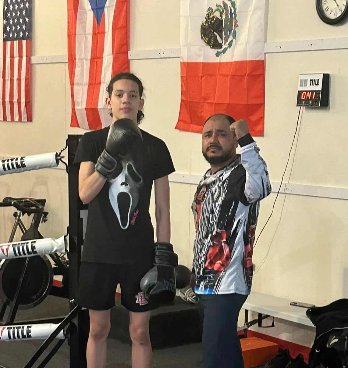 Coach and athlete training at Romero's Boxing School with US, Puerto Rico, and Mexico flags in the background