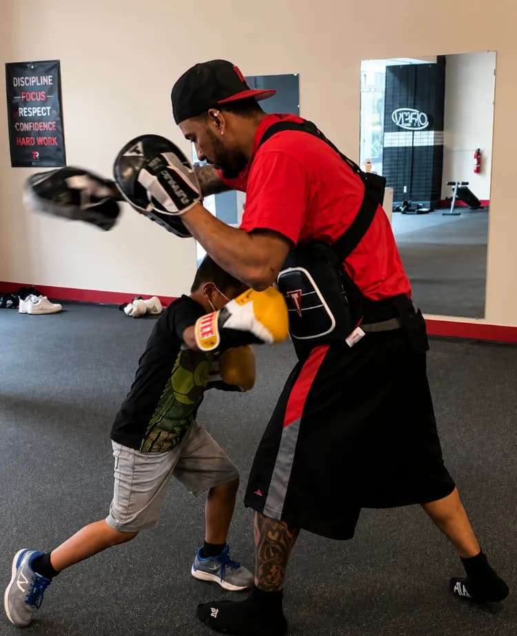 Coach doing pad work with a young athlete at Romero's Boxing School